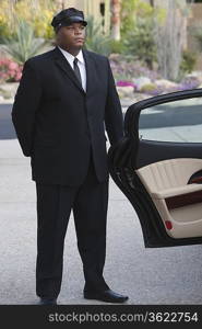 Chauffeur stands at open car door of luxury vehicle