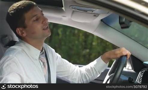 Cheating young businessman cleaning his cheek from red lipstick with napkin while sitting in car. Handsome entrepreneur found lipstick kiss on his cheek and wiping it out with napkin while looking in car rear-view mirror before driving home.