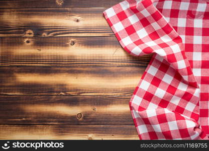 checked cloth napkin or tablecloth at rustic wooden plank board table background, top view