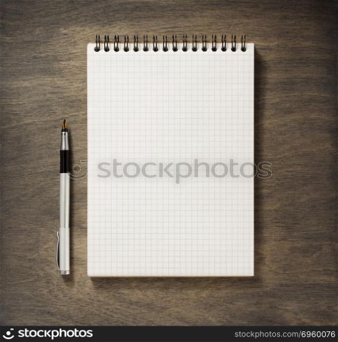 checked notebook and pen. checked notebook and pen at wooden background