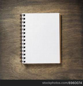 checked notebook at wood. checked notebook at wooden background