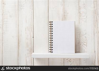 checked notebook on white wooden shelf