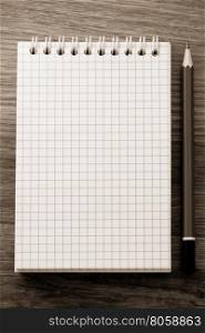checked notebook on wood background
