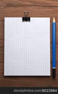 checked notepad and pencil on wood background