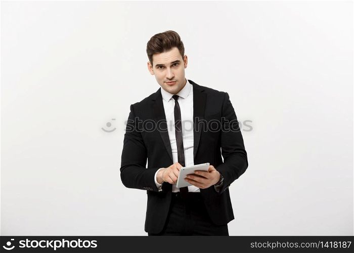 Checking statistics. Successful and confident businessman stands and checks online news on the tablet inside business center. Young business in formal suit. Checking statistics. Successful and confident businessman stands and checks online news on the tablet inside business center. Young business in formal suit.