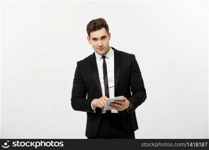 Checking statistics. Successful and confident businessman stands and checks online news on the tablet inside business center. Young business in formal suit. Checking statistics. Successful and confident businessman stands and checks online news on the tablet inside business center. Young business in formal suit.