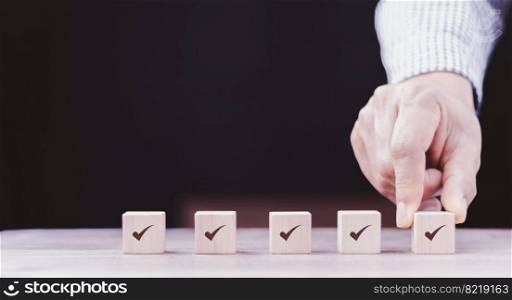 Checklist Survey and assessment concept, human hand putting cube wood with Check mark icon on wooden blocks, gray background with copy space