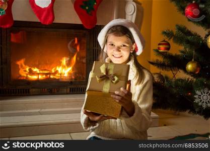 Cheerful 10 years old girl looking inside of magical glowing Christmas gift box