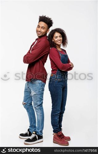 Cheerful African American man and woman with crossed hands standing back to back over isolated white background. Cheerful African American man and woman with crossed hands standing back to back over isolated white background.