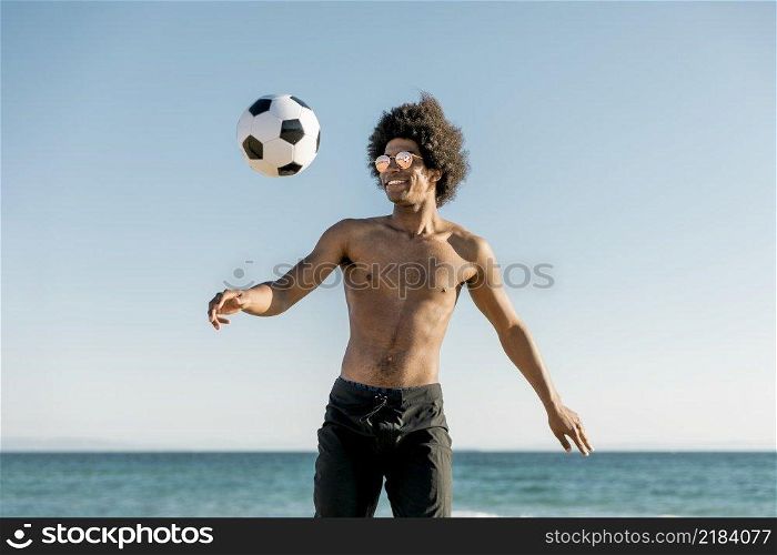 cheerful african american sportsman playing football seaside
