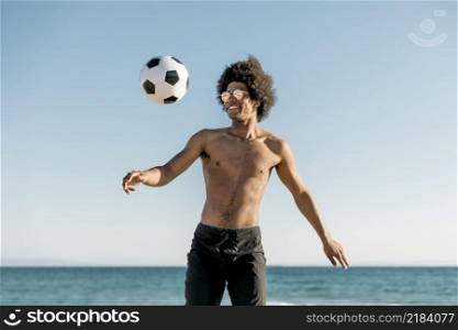 cheerful african american sportsman playing football seaside