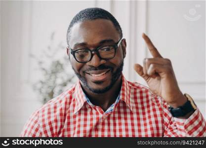 Cheerful African English tutor, glasses, explaining homework online  businessman happily conversing with colleagues on video call.