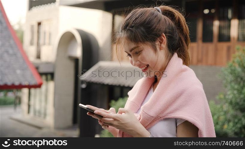 Cheerful Asian backpacker blogger woman using smartphone for direction and looking on location map while traveling at Chinatown in Beijing, China. Lifestyle backpack tourist travel holiday concept.