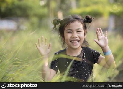 cheerful asian children kidding playing in green grass field