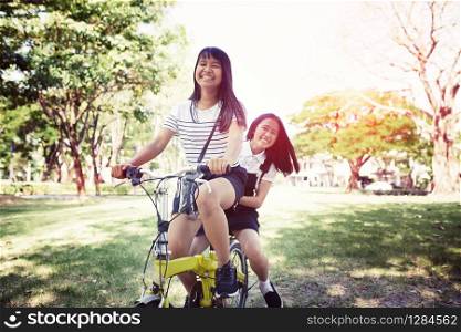 cheerful asian teenager riding bicycle in pulbic park