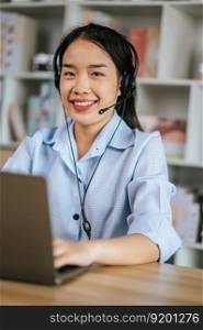 Cheerful Asian woman wear headset smiling and use laptop video call stream conference to working online while during quarantine covid-19 self isolation at home, work from home concept