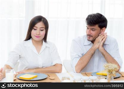 Cheerful asian young man and woman having sitting lunch and talking together at kitchen