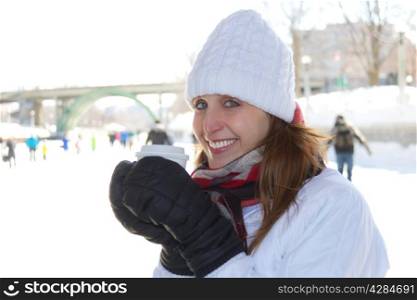Cheerful attractive woman warms up with a hot beverage on a cold winter day