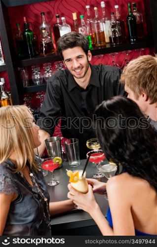 Cheerful barman chatting with young friends at cocktail bar