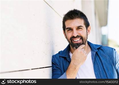 Cheerful bearded male with hand on chin while looking camera