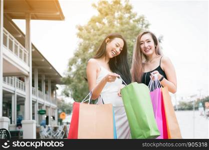 Cheerful beautiful asian female friends standing at outdoors shopping mall center retail in the city.