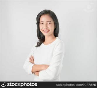 Cheerful beautiful Asian woman stand and crossed arms on gray background.