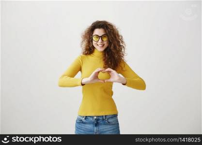 Cheerful beautiful girl making heart by hands isolated on a gray background. Cheerful beautiful girl making heart by hands isolated on a gray background.