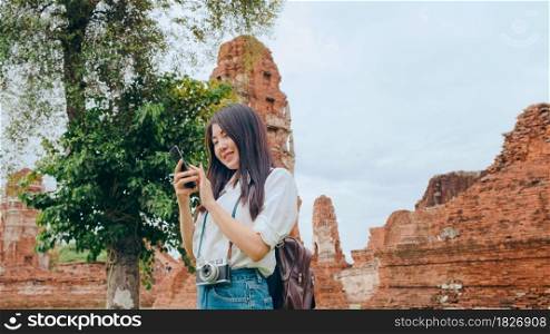 Cheerful beautiful young Asian backpacker blogger woman casual with camera look at photo on smartphone smile with happy face travel pagoda at the old city, Lifestyle tourist travel holiday concept.