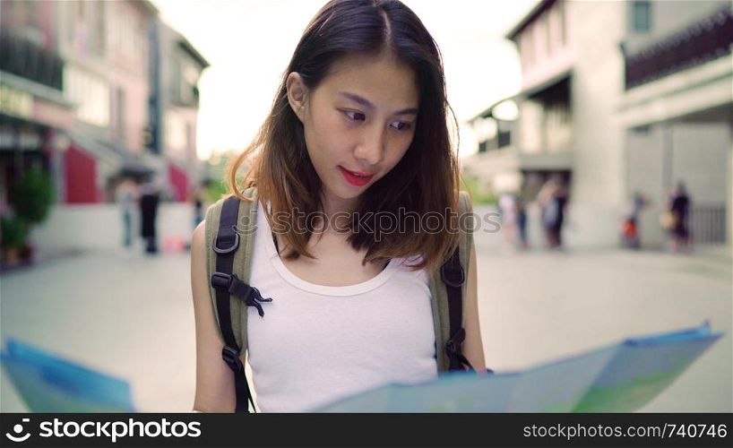 Cheerful beautiful young Asian backpacker woman direction and looking on location map while traveling at Chinatown in Beijing, China. Lifestyle backpack tourist travel holiday concept.