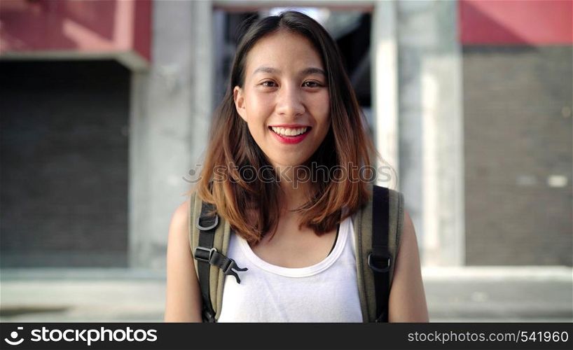 Cheerful beautiful young Asian backpacker woman feeling happy smiling to camera while traveling at Chinatown in Beijing, China. Lifestyle backpack tourist travel holiday concept.