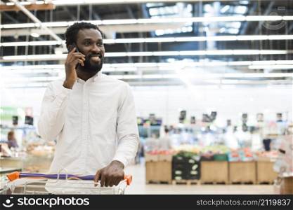 cheerful black man speaking cellphone grocery