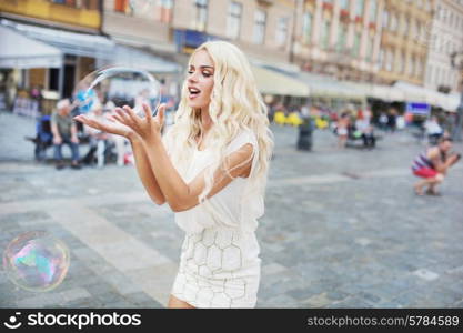 Cheerful blond lady carrying huge soap bubble