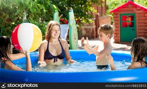Cheerful bog family playing with beach ball in inflatable swimming pool in the backyard garden. Family summer vacation and holidays.. Cheerful bog family playing with beach ball in inflatable swimming pool in the backyard garden. Family summer vacation and holidays