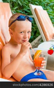 cheerful boy drinks juice at resort