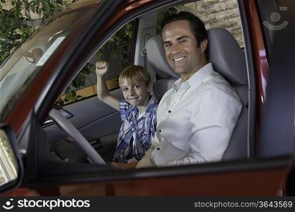 Cheerful boy sitting in car with his father