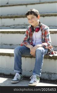 Cheerful boy sitting on bleachers at city park while looking at camera