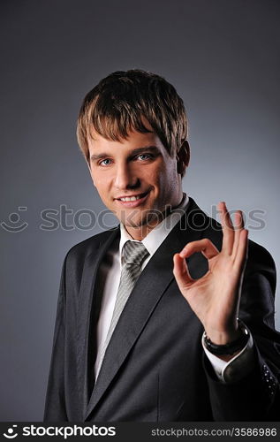 Cheerful businessman showing OK sign over grey background