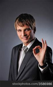 Cheerful businessman showing OK sign over grey background