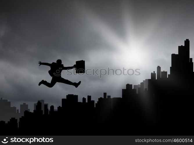 Cheerful businessman. Silhouette of businessman jumping against sunset background