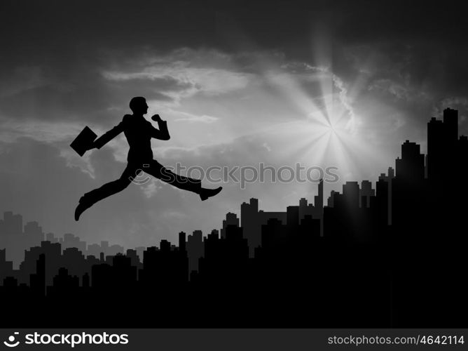 Cheerful businessman. Silhouette of businessman jumping against sunset background