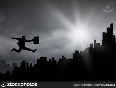 Cheerful businessman. Silhouette of businessman jumping against sunset background