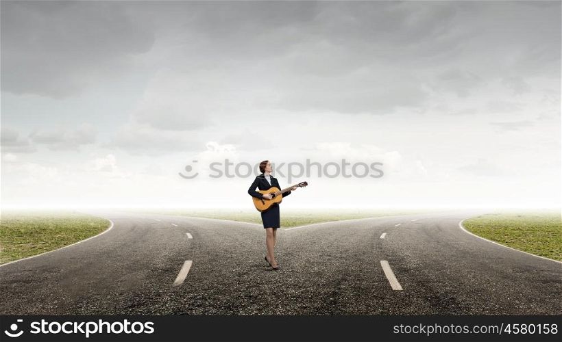 Cheerful businesswoman standing on road and playing guitar. Playing melody of success
