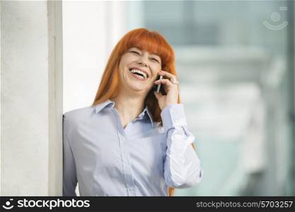 Cheerful businesswoman talking on cell phone in office
