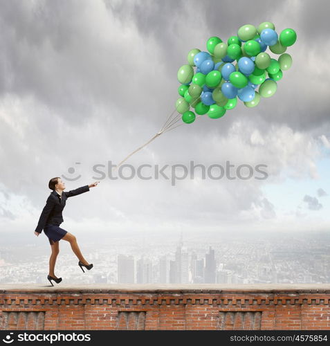 Cheerful businesswoman. Young joyful businesswoman walking with bunch of colorful balloons