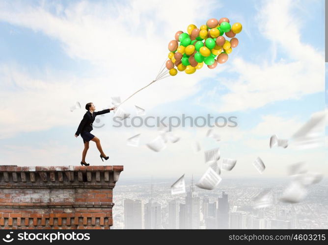 Cheerful businesswoman. Young joyful businesswoman walking with bunch of colorful balloons