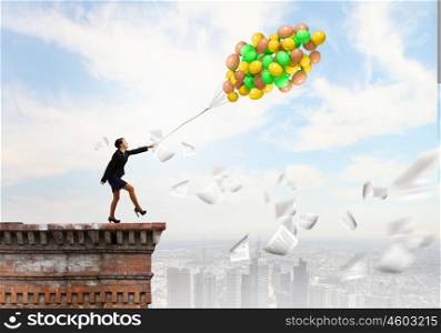 Cheerful businesswoman. Young joyful businesswoman walking with bunch of colorful balloons