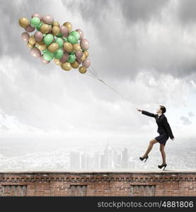 Cheerful businesswoman. Young joyful businesswoman walking with bunch of colorful balloons