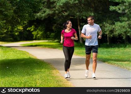 Cheerful Caucasian couple friends running in park