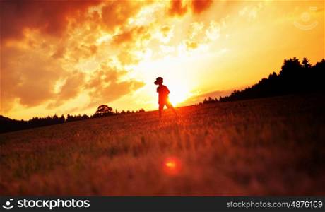 Cheerful child playing football on the meadow