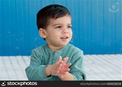 Cheerful child playing palms on the street in front of a blue wall